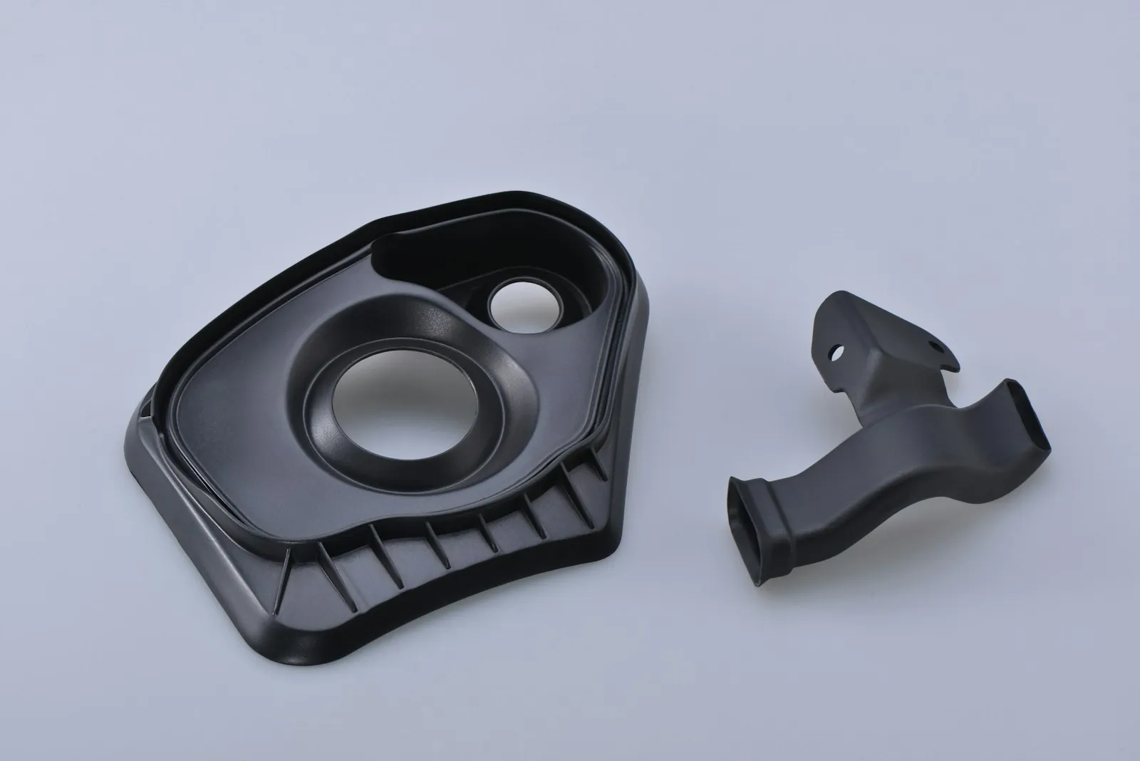 Two black injection-moulded plastic parts
